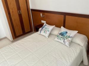 a bed with two pillows with a bird on it at Apartamentos Turísticos Los LLanos in Cuevas del Almanzora +54 photos