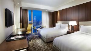 テジョンにあるLOTTE CITY HOTEL Daejeonのベッド2台とテレビがあるホテルの部屋
