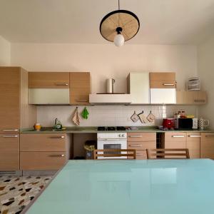 a kitchen with wooden cabinets and a light fixture at Ottantas Apartment in Spinazzola