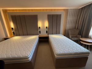 ein Schlafzimmer mit zwei Betten, einem Stuhl und einem Tisch in der Unterkunft Hotel Luxor in Burgas City