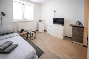 a white bedroom with a bed and a television at Apartmány Stdaniela in Bohumín
