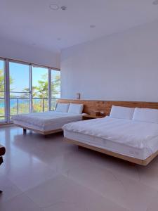two beds in a large room with large windows at 金樽浪花 in Chin-tsun