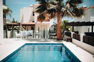 a swimming pool with a palm tree next to a house at Villa Lela in Paralimni