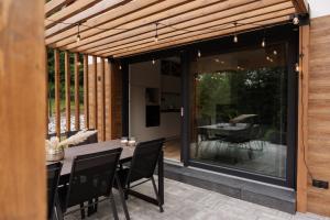 an outdoor dining area with a wooden pergola at W szczerym lesie - Domek z sauną i jacuzzi w lesie nad Jeziorem Mucharskim in Dąbrówka