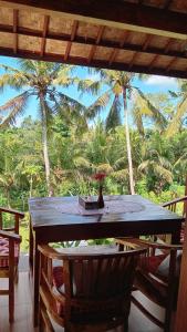 a table with chairs and a view of palm trees at Cegeng Lestari Guesthouse in Sidemen