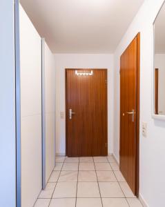 a hallway with two wooden doors and a tile floor at Kompakt und Gemütlich 1-Zimmer-Apartment in Ratingen