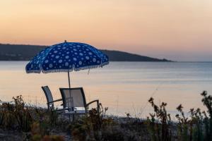 Dos sillas y una sombrilla de lunares en una playa en Shore House I Private Properties, en Quindalup
