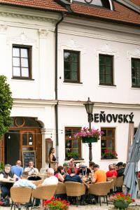 un groupe de personnes assises à des tables devant un bâtiment dans l'établissement Beňovský Apartments, à Poprad