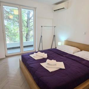 a bedroom with a purple bed with towels on it at Holiday House Hlad in Baška