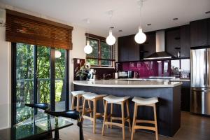a kitchen with a bar with stools and purple cabinets at Daybreaker Daylesford in Daylesford +19 photos