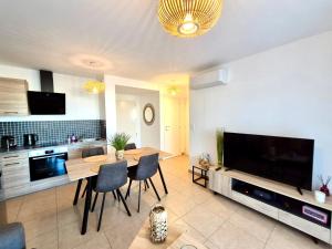 a living room with a table and a large television at T2 de standing front de mer in Propriano +13 photos