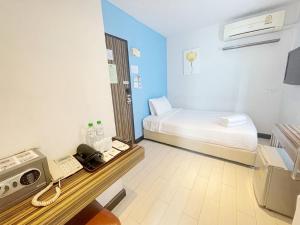 a room with a bed and a desk with a phone at Nantra Ekkamai Hotel in Bangkok