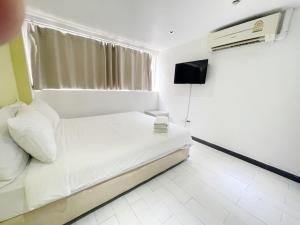 a white bedroom with a bed and a television at Nantra Ekkamai Hotel in Bangkok