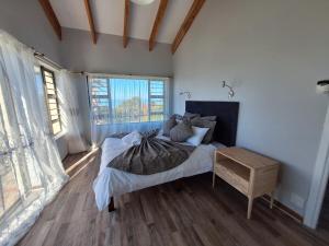 a bedroom with a bed and a large window at Barefoot Bliss Holiday Home in Port Alfred