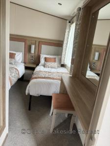 a bedroom with two beds and a desk and a mirror at Lakeside Retreat with hot tub and fishing peg on Osprey Rise at Tattershall Lakes Country Park in Tattershall