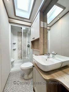 a bathroom with a sink and a toilet and a window at Lakeside Retreat with hot tub and fishing peg on Osprey Rise at Tattershall Lakes Country Park in Tattershall
