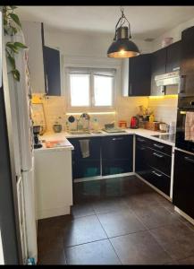 a kitchen with black and white cabinets and a window at Chambre double proche du circuit in Le Mans