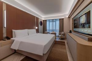 ein Schlafzimmer mit einem großen weißen Bett und einem Flachbildfernseher in der Unterkunft Orange Crystal Hotel, Shenzhen Bao'An Joy City in Shenzhen + 29 Fotos