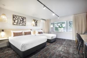 汤斯维尔Nightcap at Dalrymple Hotel的一间酒店房间，里面有两张床和一张桌子。