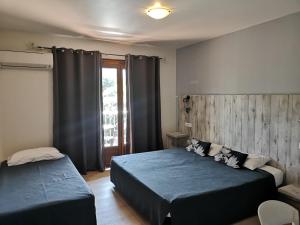 a bedroom with two beds and a window at Hotel Cyrnea in Calvi