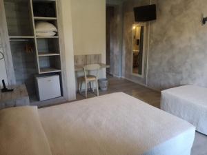 a room with two beds and a table and a television at Hotel Cyrnea in Calvi