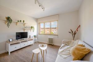a white living room with a couch and a tv at Escapada a la montaña San Martín in Sotrondio