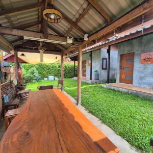 a large wooden table in the middle of a patio at Kedthawa Homestay เฮือนภูผา in Ban Cho Lae +63 photos