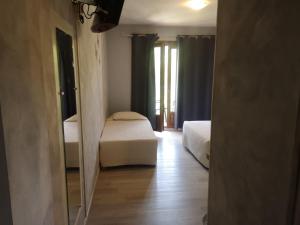 a hotel room with two beds and a mirror at Hotel Cyrnea in Calvi