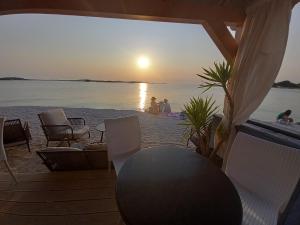 a sunset on the beach with chairs and a table at Apartman Renata in Pula