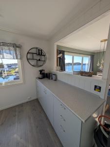 a kitchen with white cabinets and a counter top at Flott hytte skjærgård Lindesnes in Svinøy +6 photos