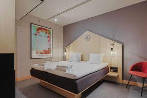 um quarto com uma cama grande e uma cadeira vermelha em Hotel With Urban Deli em Estocolmo
