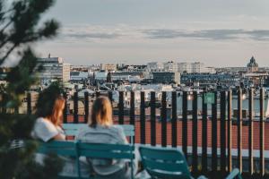 duas mulheres sentadas em um banco olhando para uma cidade em Hotel With Urban Deli em Estocolmo