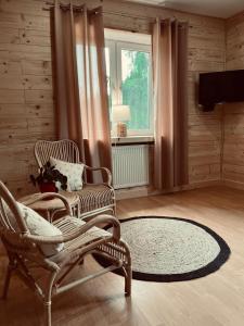 a living room with two chairs and a window at Nad stawami - apartament in Białowieża
