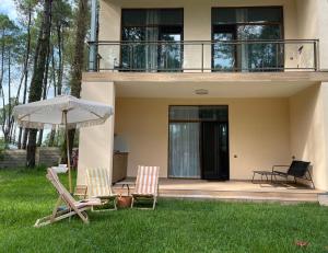 two chairs and an umbrella in front of a house at Villa on the sands in Ureki