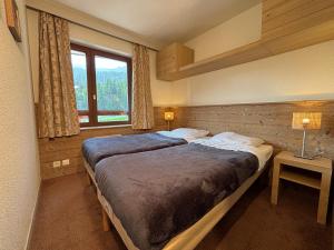 a bedroom with two beds and a window at Résidence Britania Clés Blanches in La Tania