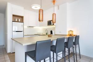 a kitchen with white cabinets and a island with blue chairs at Two modern and bright apartments near el Duque beach in Adeje +33 photos