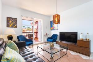 a living room with a couch and a tv at Two modern and bright apartments near el Duque beach in Adeje