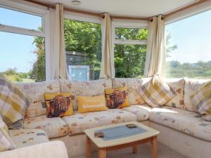 un sofá blanco en una sala de estar con ventanas en The Lodge, en Amlwch 16 fotos más