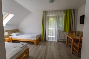 a bedroom with two beds and a table and a window at Diás Panzió in Orfű