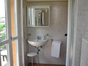 een badkamer met een wastafel, een spiegel en een kruk bij La Collina in Casnate con Bernate