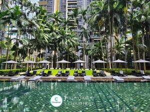 a swimming pool with lounge chairs and palm trees at St Mary Kuala Lumpur Homestay Bathtub & Walk to Pavilion Bukit Bintang by Cloud Host in Kuala Lumpur