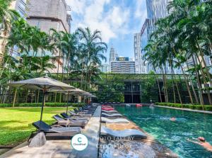 a pool with lounge chairs and an umbrella in a city at St Mary Kuala Lumpur Homestay Bathtub & Walk to Pavilion Bukit Bintang by Cloud Host in Kuala Lumpur