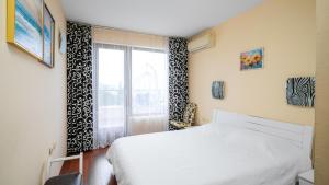 a bedroom with a bed and a window at Превъзходен апартамент Къщата на Мечтите-Златни пясъци на първа линия in Varna City
