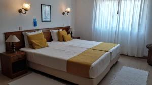 a bedroom with a large bed with yellow pillows at Boutique Hotel Marina S. Roque in Lagos