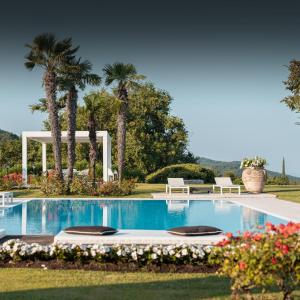 a swimming pool with two chairs and palm trees at Luxury Villa on Garda Lake in Torri del Benaco