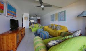 a living room with yellow couches and a flat screen tv at 24 Isikhulu Umdloti Beachfront in Umdloti