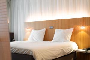 a bedroom with a bed with white sheets and pillows at Resort Bad Boekelo - Hotel met Spa & Wellness in Enschede in Enschede