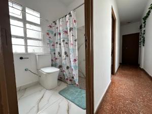 Un baño con inodoro y cortina de ducha. en Habitación individual con baño compartido, en Algeciras