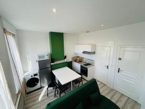 een kleine keuken met een witte tafel en een groene muur bij Appartement Nid Douillet Plus in Tourcoing +17 foto's