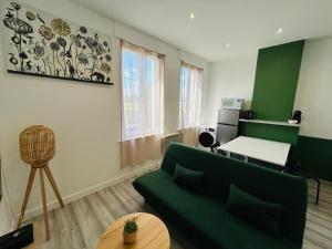 een woonkamer met een groene bank en een tafel bij Appartement Nid Douillet Plus in Tourcoing